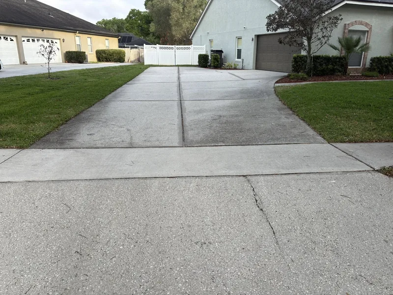 Dull gray-stained long driveway before cleaning