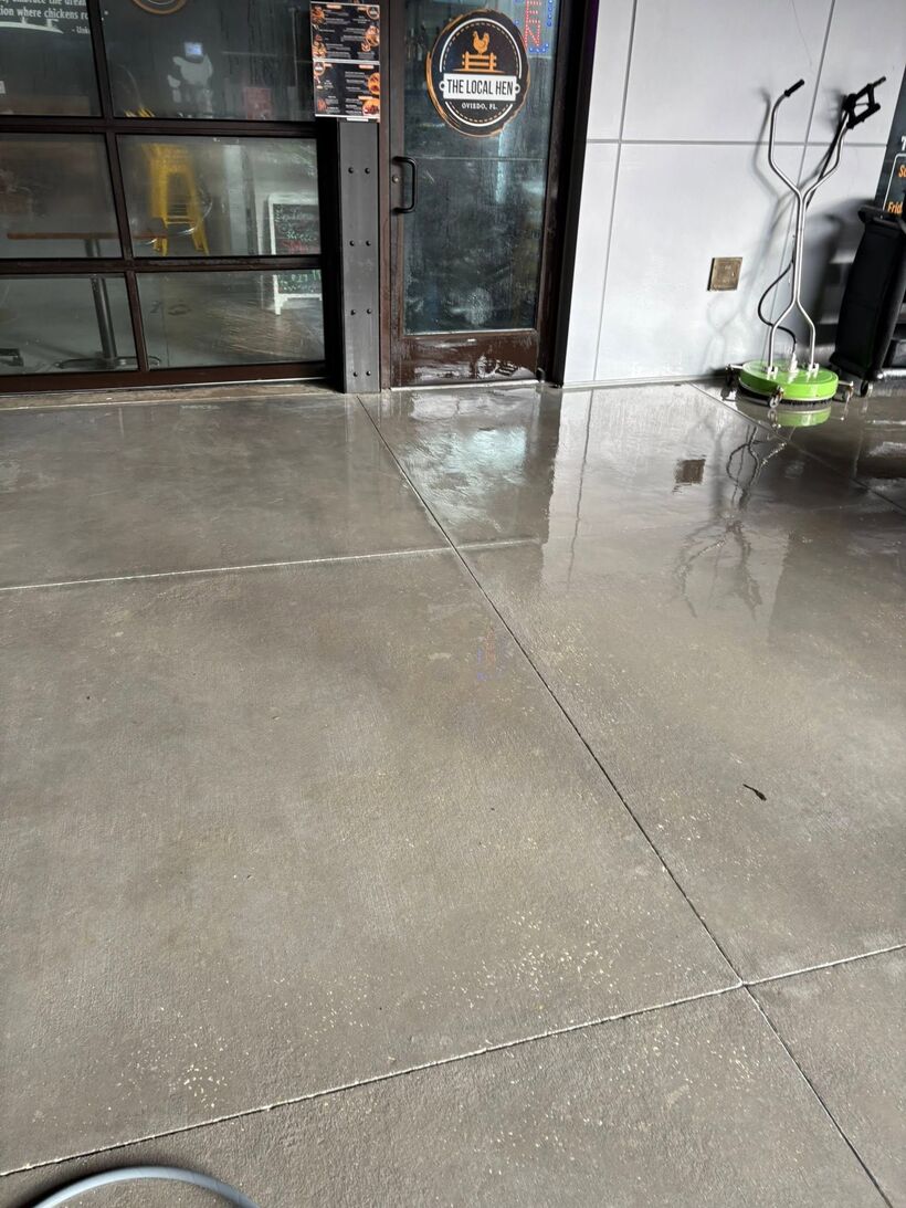 Surface cleaner mid-pass at The Local Hen entrance, a crisp clean line across the concrete